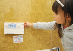 エコキュートのリモコンを操作する子供の画像